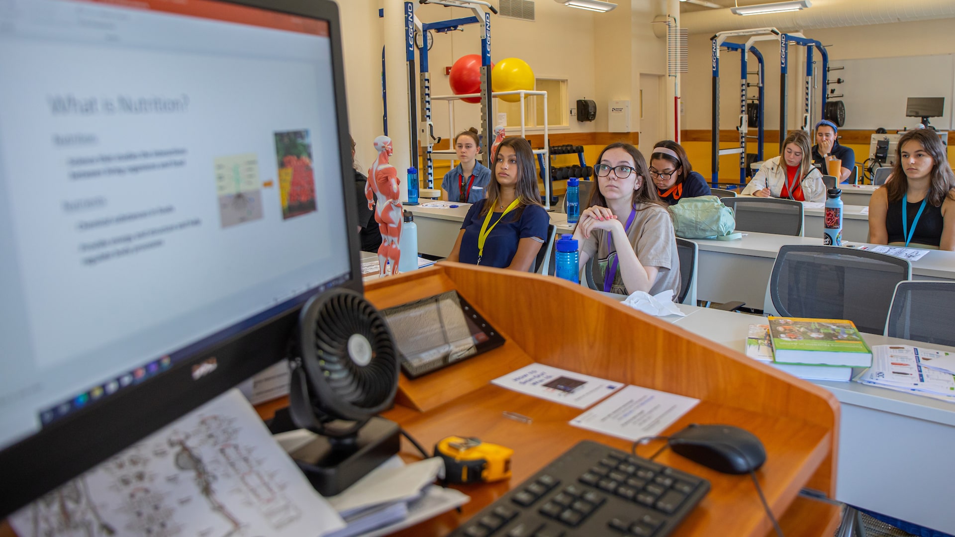 Students facing the front of a classroom with a computer screen flashing, u201cWhat Is Nutrition?u201d